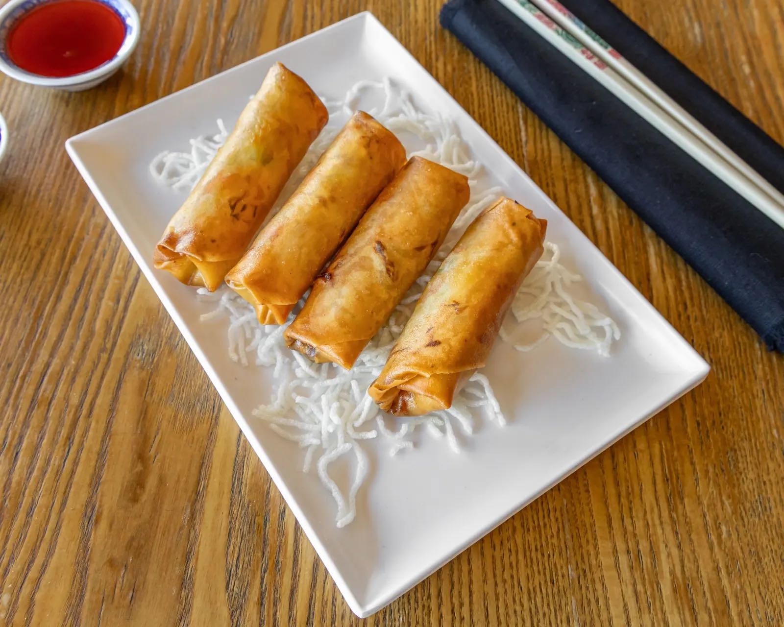 Golden spring rolls on crispy noodles with sweet and sour dipping sauce